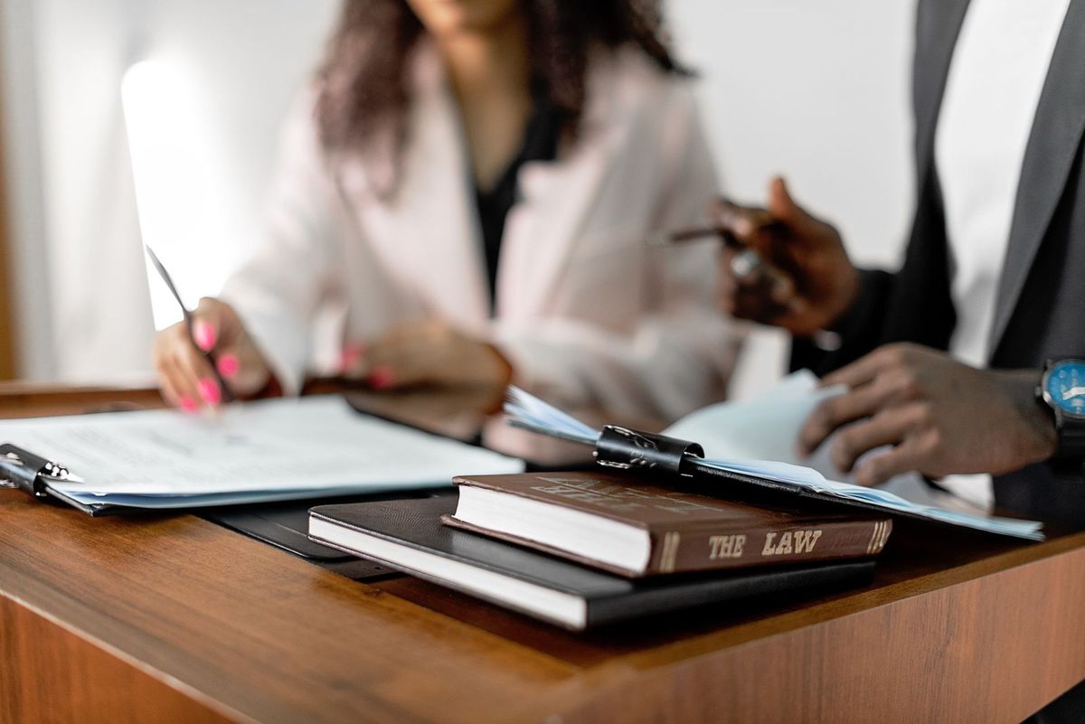 Deux individus signent des documents sur une table avec des livres et des dossiers