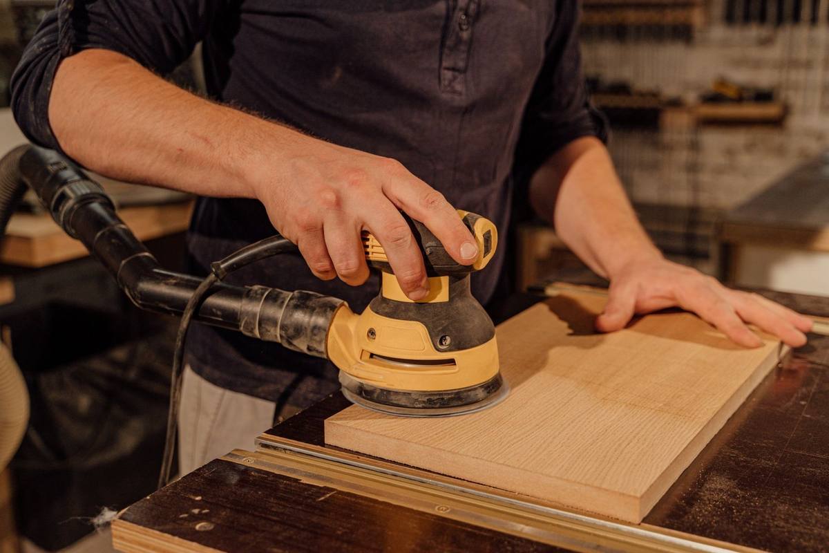 Homme utilisant une sabreuse jaune sur une planche de bois dans un atelier